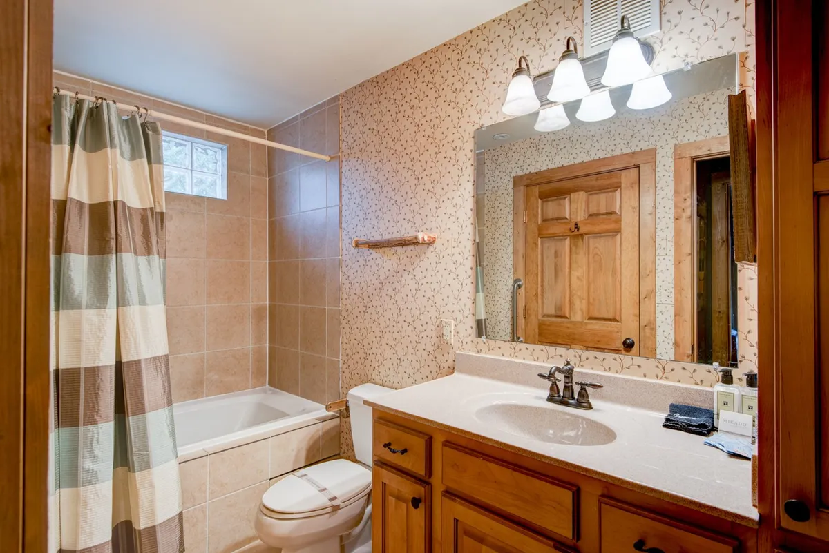 A calm, refreshing bathroom space with a vanity, sink, mirror, bathtub, and shower curtain. The ambiance suggests a soothing retreat for self-care and relaxation, ideal for soaking tired muscles.