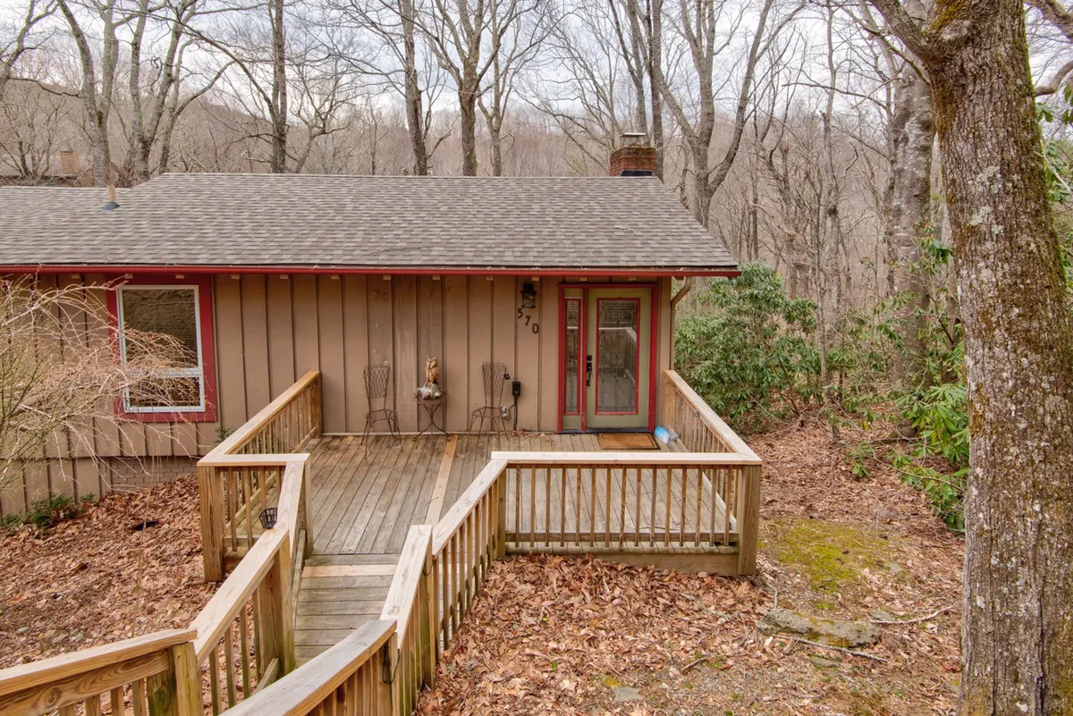 This image captures the wooden deck at the front entrance of the home, surrounded by tall trees. The scene evokes the feeling of being nestled in the Appalachian forest, and the deck itself offers a space for relaxing after a day spent skiing or hiking. The natural setting emphasizes the cabin's proximity to outdoor adventure.